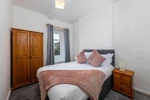 a bedroom with a large bed with a wooden cabinet at Muncaster Cottages in Ravenglass