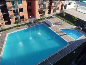 a large blue swimming pool in front of a building at Apartamento Vacacional Toscana Melgar in Melgar
