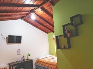 1 dormitorio con 1 cama y TV en la pared en Hotel y Restaurante Las Gardenias, en El Remate