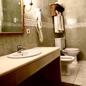 a bathroom with a sink and a toilet and a mirror at Hotel Portofoz in Porto
