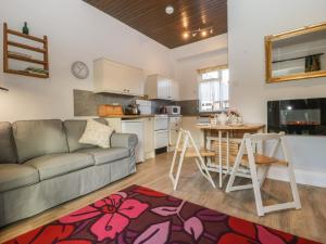 a living room with a couch and a table and a kitchen at Stable Cottage in Taunton