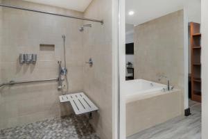 a bathroom with a tub and a shower with a bench at Hotel Casa 425 + Lounge, A Four Sisters Inn in Claremont