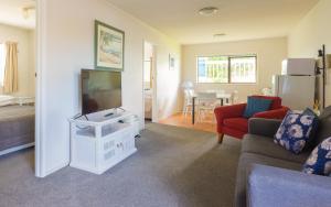 a living room with a couch and a tv at Snells Beach Motel in Snells Beach