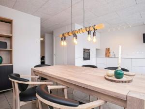 a kitchen and dining room with a wooden table and chairs at 8 person holiday home in Bl vand in Blåvand