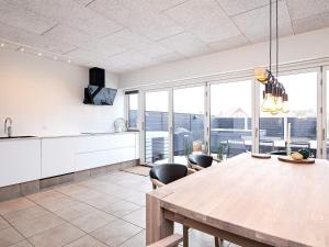 a kitchen with a table and some chairs and windows at 8 person holiday home in Bl vand in Blåvand