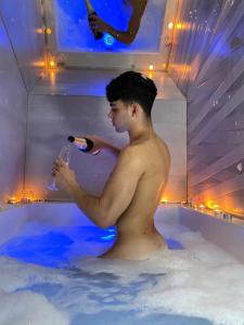 un hombre en una bañera sosteniendo una botella de champán en Love in the Loft, en Babilafuente
