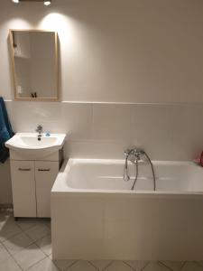 La salle de bains blanche est pourvue d'une baignoire et d'un lavabo. dans l'établissement Apartament Hoża, à Szczecin