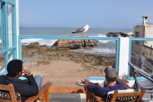 a group of people sitting on a balcony looking at the ocean at Riad Kafila in Essaouira