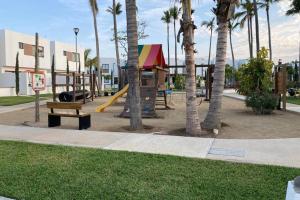 a park with a playground with a slide and palm trees at Preciosa Enjoyable Casa 12 Personas Alberca Playa Coto 24H in Mazatlán