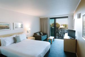 バリナにあるRamada Hotel & Suites by Wyndham Ballina Byronのベッドとテレビが備わるホテルルームです。