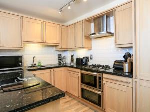 a kitchen with wooden cabinets and black counter tops at 14 Combehaven in Salcombe