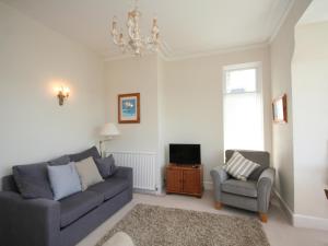 a living room with a couch and a chair and a tv at 1 Hazeldene in Salcombe