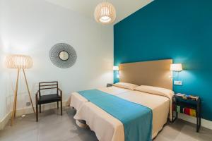 1 dormitorio con cama y pared azul en Debambú Larios, en Málaga