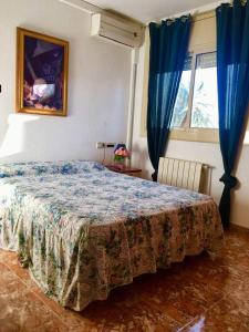 a bedroom with a large bed with blue curtains at Casa La Luna Cambrils in Cambrils