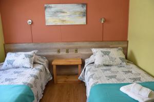 um quarto com duas camas e uma mesa em Asói Hostal em Puerto Natales