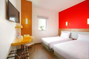a hotel room with two beds and a desk and a tv at Amaris Hotel Sunset Road - Bali in Kuta