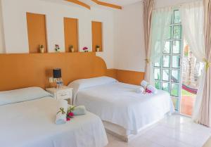 two beds in a room with a window at Hotel Lagoon - Pet Friendly in Chetumal