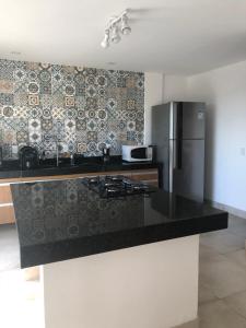 Una cocina con encimera negra y refrigerador. en Casa espaçosa cpm linda vista pro verde, en Búzios