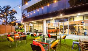 un restaurante con mesas y sillas frente a un edificio en ibis Melbourne - Glen Waverley, en Glen Waverley
