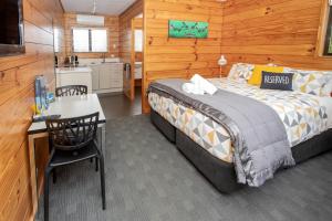 1 dormitorio con cama, escritorio y cocina en Hanmer Springs TOP 10 Holiday Park, en Hanmer Springs