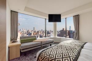 a hotel room with a bed and a view of a city at Hotel Vista Osaka Namba in Osaka