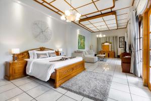 a bedroom with a large bed and a living room at Raintree Boutique Villa & Gallery in Yogyakarta