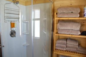 a bathroom with a shower and some towels on a shelf at Yellowstone's Treasure Cabins in Gardiner