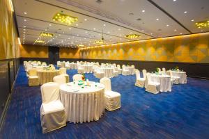 a banquet hall with white tables and white chairs at Citadel Hotel By Vinnca in Hyderabad