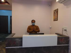 a man wearing a mask sitting at a desk with a laptop at Rukmani Inn in Vrindāvan