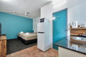 a kitchen with a refrigerator in a room with a bed at Capitanos in Darwin