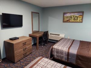 een hotelkamer met een slaapkamer met 2 bedden en een bureau bij Travelodge by Wyndham Barstow in Barstow