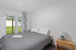 een witte slaapkamer met een bed en een raam bij Kohi Point - Ohope Beachfront Holiday Home in Ohope Beach