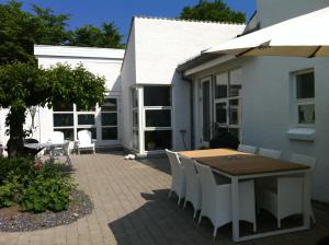 a patio with a wooden table and white chairs at Kathrines Bed & Breakfast in Svendborg