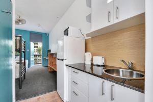 a kitchen with a sink and a refrigerator at Capitanos in Darwin