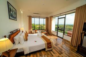 a bedroom with a large bed and a large window at Centauria Wild in Udawalawe