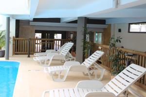 a row of white lounge chairs next to a pool at Sikamifer Tourist Resort in Quatre Bornes