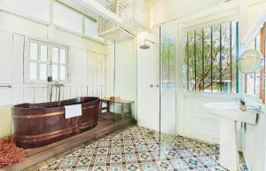 ein Badezimmer mit einer Holzbadewanne und einem Waschbecken in der Unterkunft Temple Tree Resort in Pantai Cenang