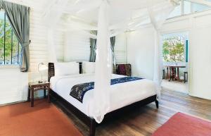 a bedroom with a white bed with a canopy at Temple Tree Resort in Pantai Cenang