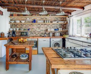 a kitchen with white appliances and a wooden table at De Kale Kat in Greyton