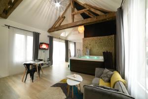 een woonkamer met een bank en een bad bij Eaudyssée maison avec SPA privée - Loiret in Ladon