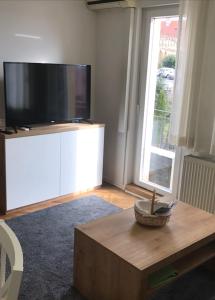 uma sala de estar com uma televisão grande e uma mesa de centro em Apartman SLAVONIA 3 em Ðakovo