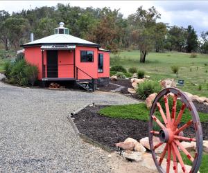 a red building with a wheel in a yard at A Stanthorpe Getaway in Ballandean