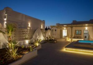 a house with a courtyard with a swimming pool at night at Dafnes Villa with Private Plunge Pool in Perivolos