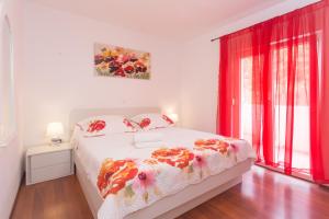 Schlafzimmer mit einem Bett und einem Fenster mit roten Vorhängen in der Unterkunft Villa Tomic in Trnbusi