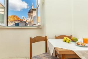 a table with a plate of fruit and a view of a building at Apartments Placa Dubrovnik in Dubrovnik