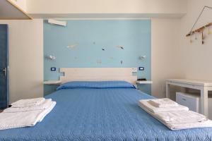 a bedroom with a blue bed with towels on it at Maresidence - il Residence sul mare a Torre Pali in Torre Pali