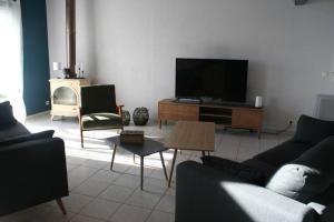 een woonkamer met banken en een flatscreen-tv bij Moulin de Bigorre in Saint-Genès-de-Castillon