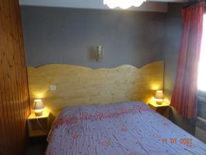 ラ・ブレスにあるLa Bresse Hautes Vosges Chalet Le Podentのベッドルーム1室(大型ベッド1台、木製ヘッドボード付)