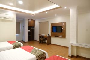 a hotel room with two beds and a desk at Joyful Hotel in Tanjungpandan