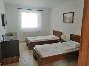 two beds in a room with a window at Motel Senec in Senec